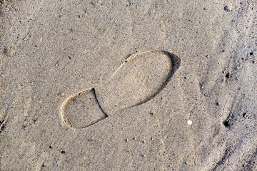 Fototapeta na wymiar Footprint of a boot on the wet sea sand