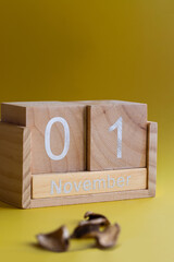 All Saints Day. Angel, wooden calendar and yellow autumn leaf