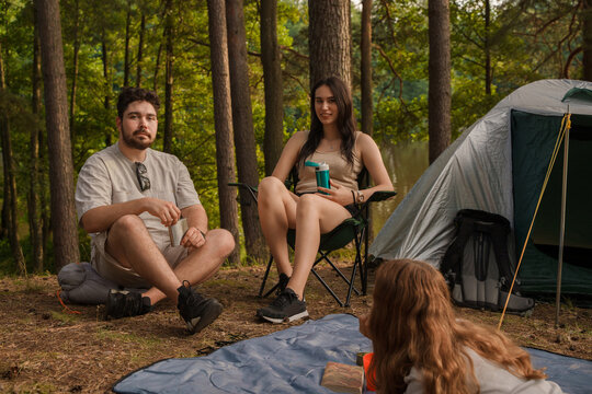 Photo of three friends with food and drink resting on their weekend in forest journey.