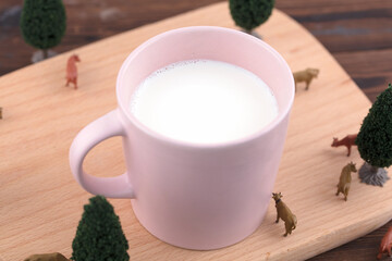 A glass of milk and a cow model on a cutting board