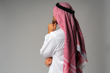 Back view of young Arab man standing on gray background