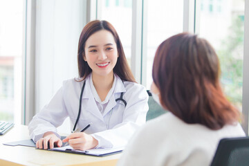 Asian professional doctor woman who wears medical coat talks with female patient to suggest treatment guideline and healthcare concept in office of hospital.