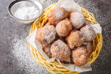 Sweet donuts oliebollen with raisins and powdered sugar close-up in a basket on the table....