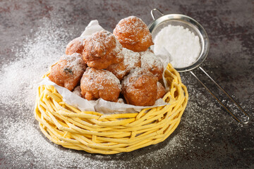 Sweet donuts oliebollen with raisins and powdered sugar close-up in a basket on the table....