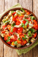 Roasted aubergine salad kozlenmis patlıcan salatası with roasted peppers, onions, tomatoes and garlic closeup in the bowl on the table. Vertical top view from above
