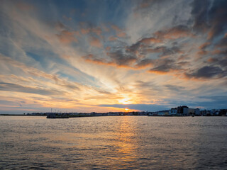 Dramatic sunset over Galway city and bay. Beautiful sky with warm and cool tones over city buildings silhouette. River Corrib and the Long walk area of the city.