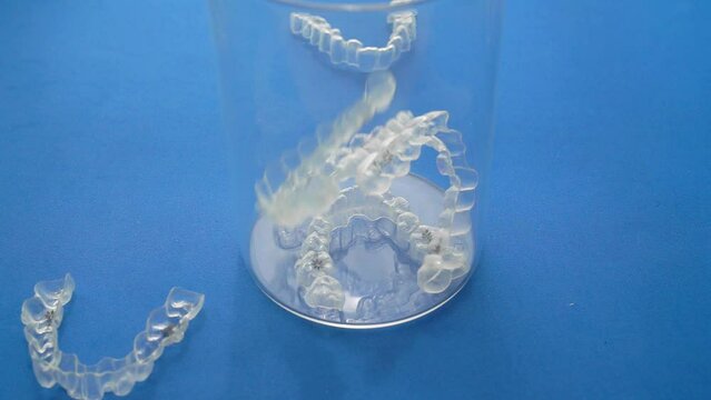 Multiple orthodontic clear aligners fall randomly. Slow motion footage.