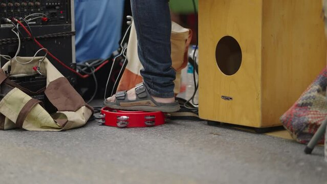 A close up shot of a man playing percussion by his feet in the morning. Only one leg is seen in the video