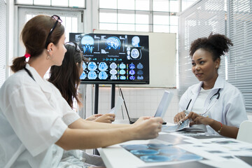Team of medical doctor meeting in the brain research laboratory by monitor showing MRI, CT scans brain images. Group of female doctor discussing surgery and treatment with medical x-ray scan papers