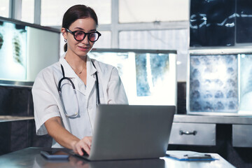 Female doctor checking anatomy and physiology x-ray film of patient on laptop computer in the...