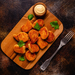 Fried crispy chicken nuggets on a wooden serving board.