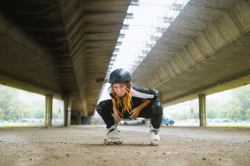 Young active woman wearing roller blades and protection gear squatting