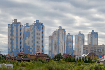 Obraz premium Modern stylish multi-storey residential building against the cloudy sky, on a summer day. Construction industry. Urban architecture, built residential buildings