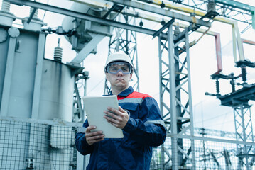 An energy engineer inspects the modern equipment of an electrical substation before commissioning....
