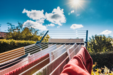 Drying wet clothes ecofriendly in the sun on a drying rack during summer after laundry without an...
