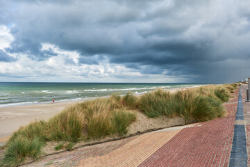 breakwater and marram grass over dunes and storm clouds at Malo-Les-Bains beach in Dunkirk, france
