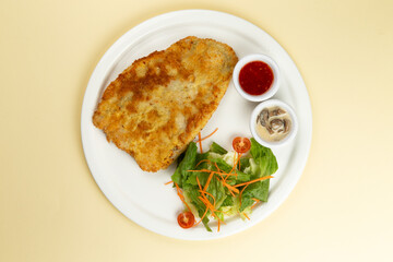 Turkey schnitzel and salad in a plate on a light background.