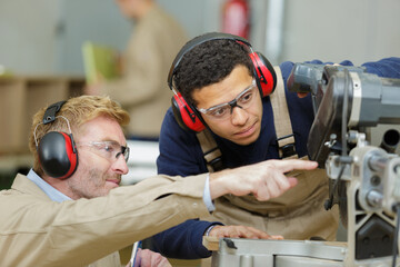young apprentice with teacher working on piece of wood