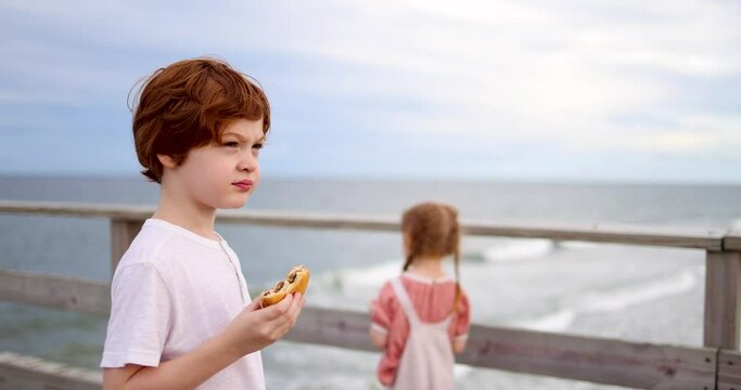 redhead kids in the pier, eating sandwiches and enjoying the summer evening on the ocean coast