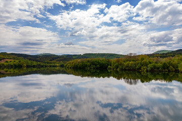 Fototapeta na wymiar Landscape at the lake with calm water, trees reflection, and beautiful sky