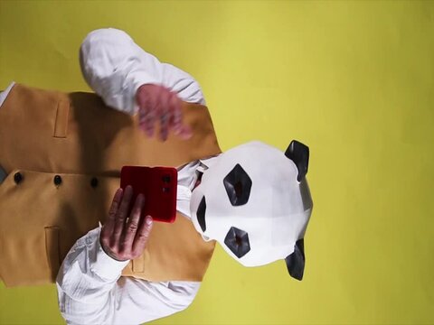 Sad man with panda mask receiving bad news on his mobile phone. Video in vertical format