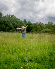 Woman enjoying mindfulness on dog walk and in a meadow of flowers and grass.