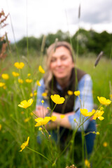 Woman in meadow of flowers and grass enjoying some wellbeing/mental relaxation. 