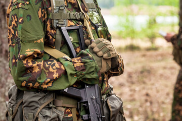 Close up hands russian soldier man dressed military camouflage uniform with machine gun in woodland at nature background. Male border guard in country border holding weapon on war. Copy text space