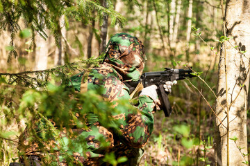 Russian soldier man dressed military camouflage uniform with weapon in woodland at nature background, rear view. Male border guard in country border with autogun on war. Copy text space