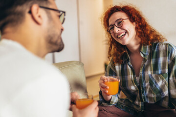 Happy young couple enjoying fresh orange juice for a breakfast at home