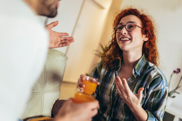 Happy young couple enjoying fresh orange juice for a breakfast at home