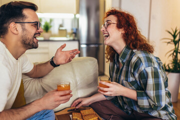 Happy young couple enjoying fresh orange juice for a breakfast at home