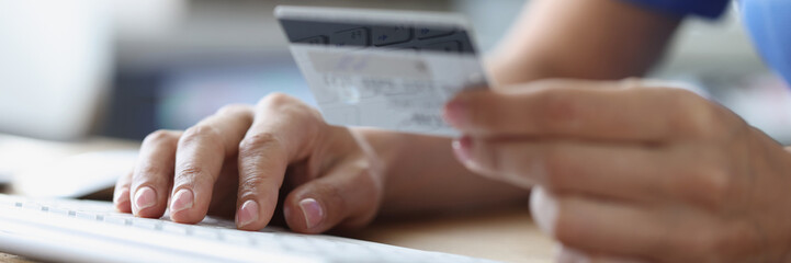 Person holds credit bank card and computer keyboard