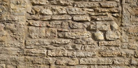 Texture of a beige stone wall. Smooth, cracked surface. Old castle wall of stone different shape....