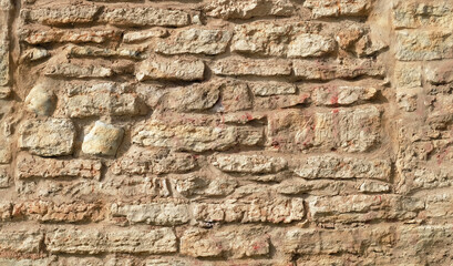Texture of a beige stone wall. Smooth, cracked surface. Old castle wall of stone different shape. Part of a stone wall, for background or texture. 