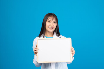 Smiling doctor holding blank banner or card with stethoscope on blue background