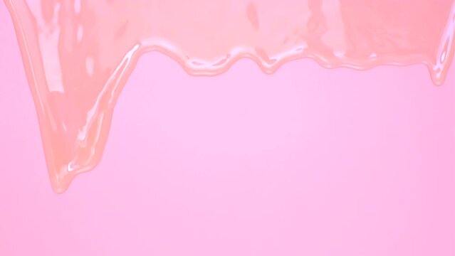 liquid shampoo dripping down on pink background close-up.