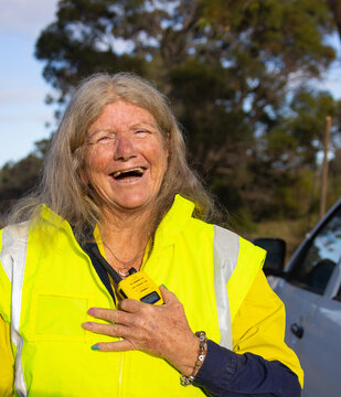 female worker outdoors wearing hi-vis and holding 2-way radio