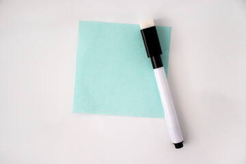 A blank piece of paper on the door of the white refrigerator. A paper note with a felt-tip pen...