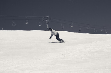 Snowboarder descends on snowy ski slope and sky with snow. Black and white retro toned image. - 532389535
