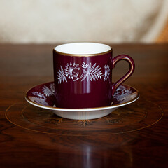 antique dark red porcelain service with national painting. an old cup in Ukrainian style in a luxury interior. ceramics close-up