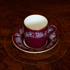 antique dark red porcelain service with national painting. an old cup in Ukrainian style in a luxury interior. ceramics close-up