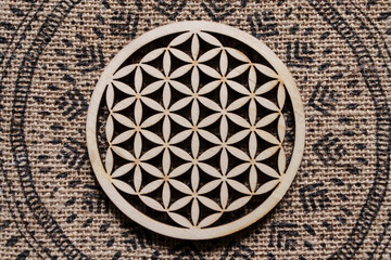 Wooden flower of life on the background of a hemp tablecloth with an ornament.