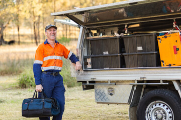 Happy male handyman with toolbox bag laughing near tradie ute