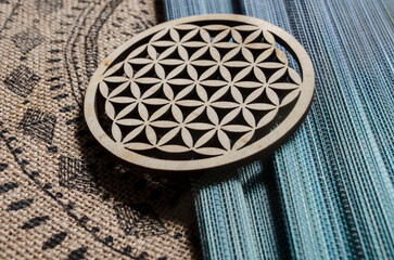 Wooden flower of life on the background of a hemp tablecloth with an ornament. - 532392348