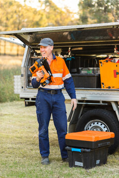 Handyman with nail gun power tool beside tradie ute
