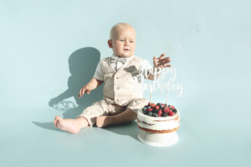 Happy, surprised one year baby boy eats sweets. Toddler boy and first healthy homemade birthday...