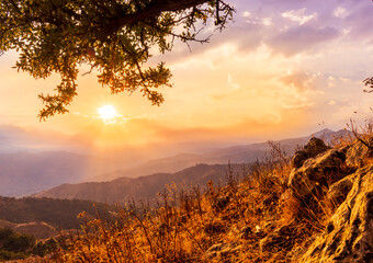 beautiful view from highland with tree on a mountain slope to a mountains and sunset or sunrise valley with amazing sky with clouds and glow