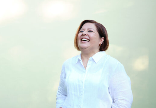 Laughing middle aged woman with short hair wearing white shirt