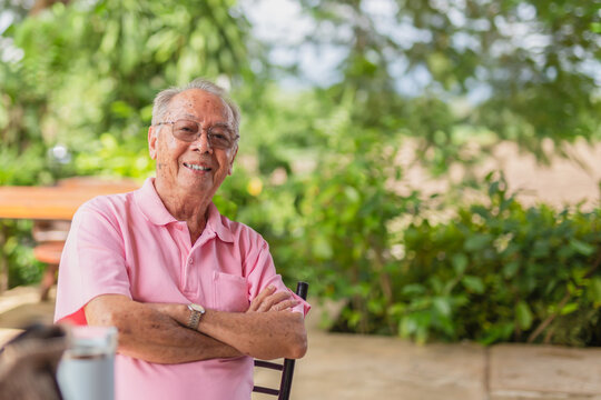 Portrait asian elderly man 83 years old with toothy smile sitting outdoor in the garden.